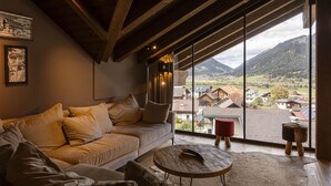 A cozy living room with a large window offering a view of a village and mountains. - Premium penthouse with 4 bedrooms (Ehrwald)
