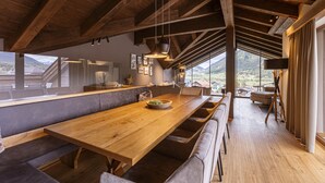A spacious kitchen with a long wooden table, built-in seating, and large windows offering a mountain view. - Premium penthouse with 4 bedrooms (Ehrwald)
