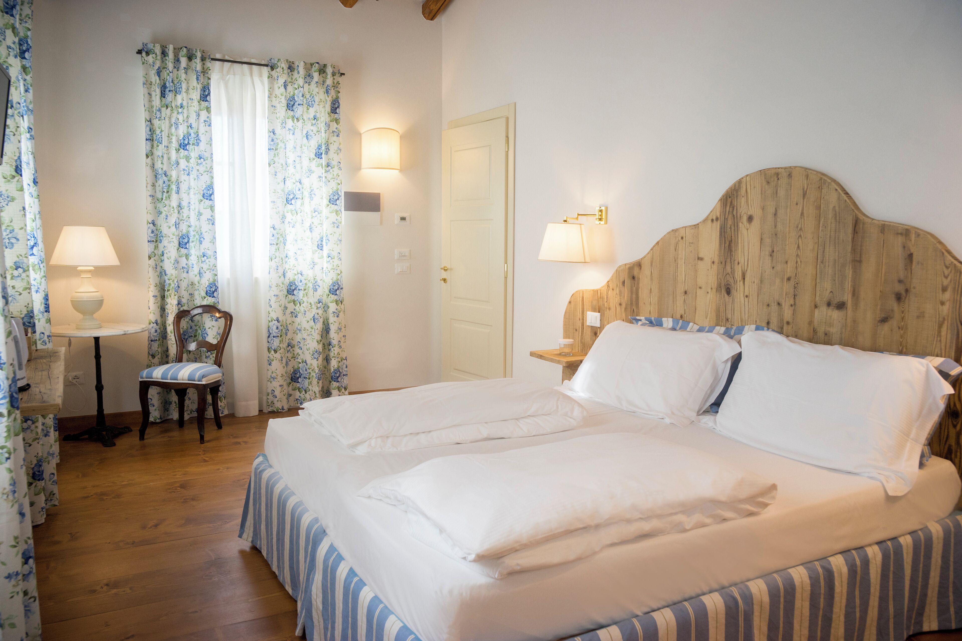 A bedroom with a double bed, a chair, a bedside table, and a lamp.