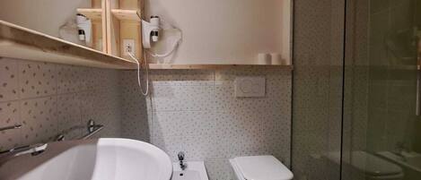 A bathroom with a large sink, a bidet, a toilet, and a glass shower enclosure.