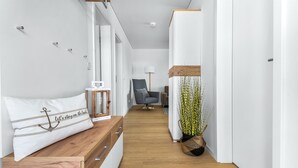 Ein moderner, minimalistischer Flur mit einer Holzbank, einer Lampe, einem Sessel und einem Blumentopf.