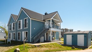 Ein zweistöckiges Haus mit Balkon, einer Veranda und einem kleinen Anbau.