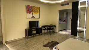 A modern living room with a flat-screen TV, a dining table, and chairs.