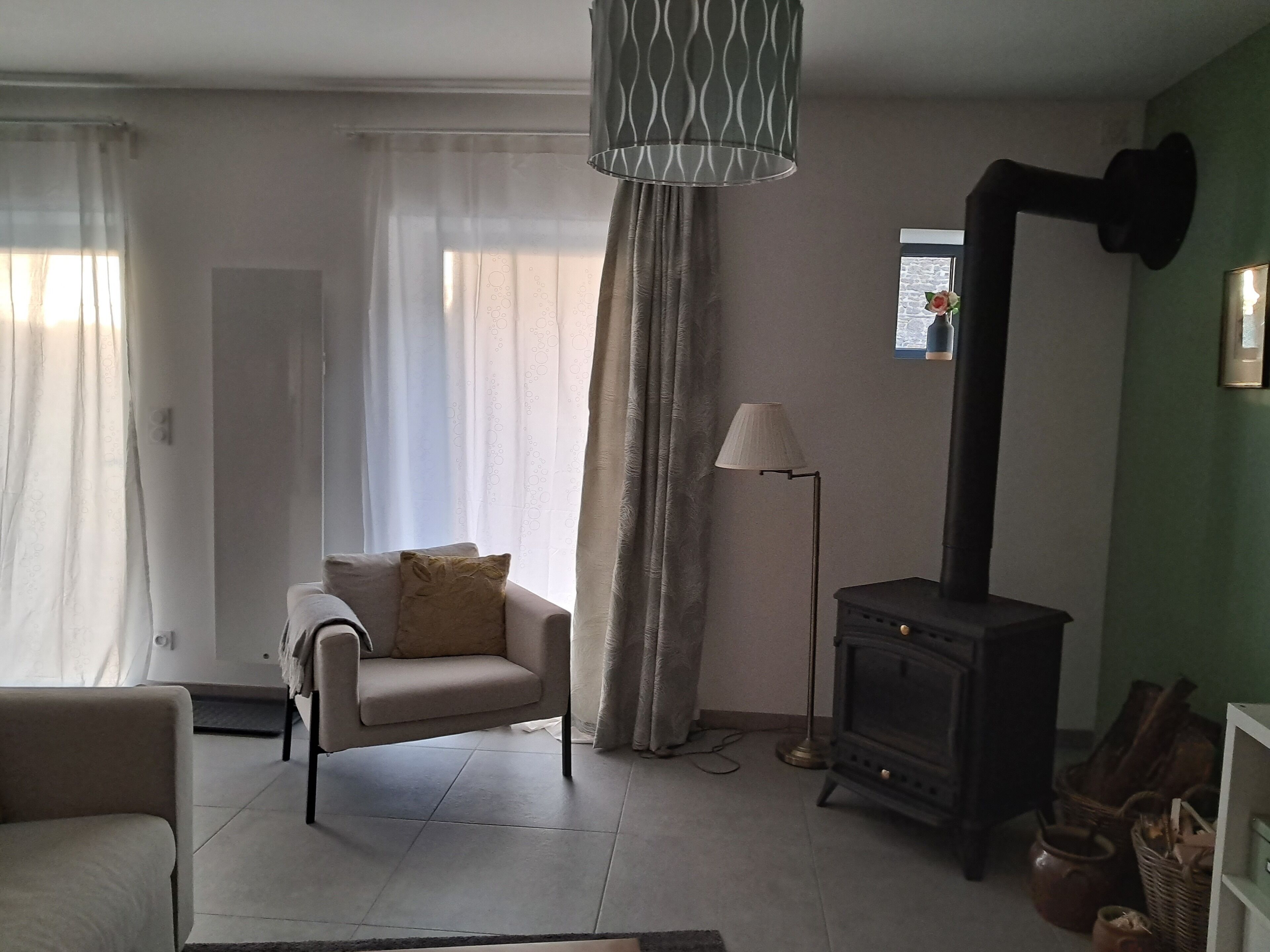 Una sala de estar con sofá, lámpara, chimenea y ventana con cortinas.