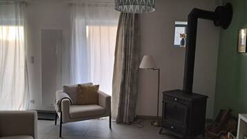 Una sala de estar con sofá, lámpara, chimenea y ventana con cortinas.