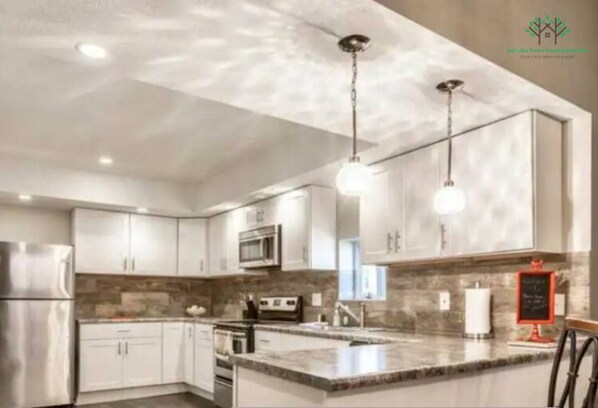 A modern kitchen with white cabinets, a built-in oven, and a large island. - Completely updated home a few blocks from the Historic Independence Square (Independence)