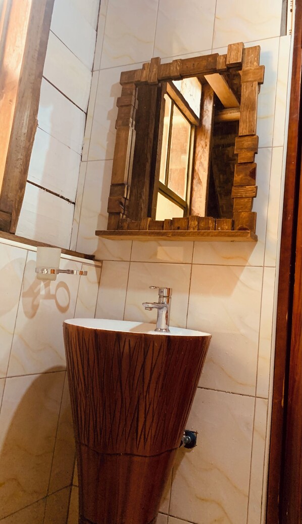 A bathroom with a wooden vanity, a sink, and a mirror with a wooden frame. - Bugoma sand beach resort hotel (Bugala Island)