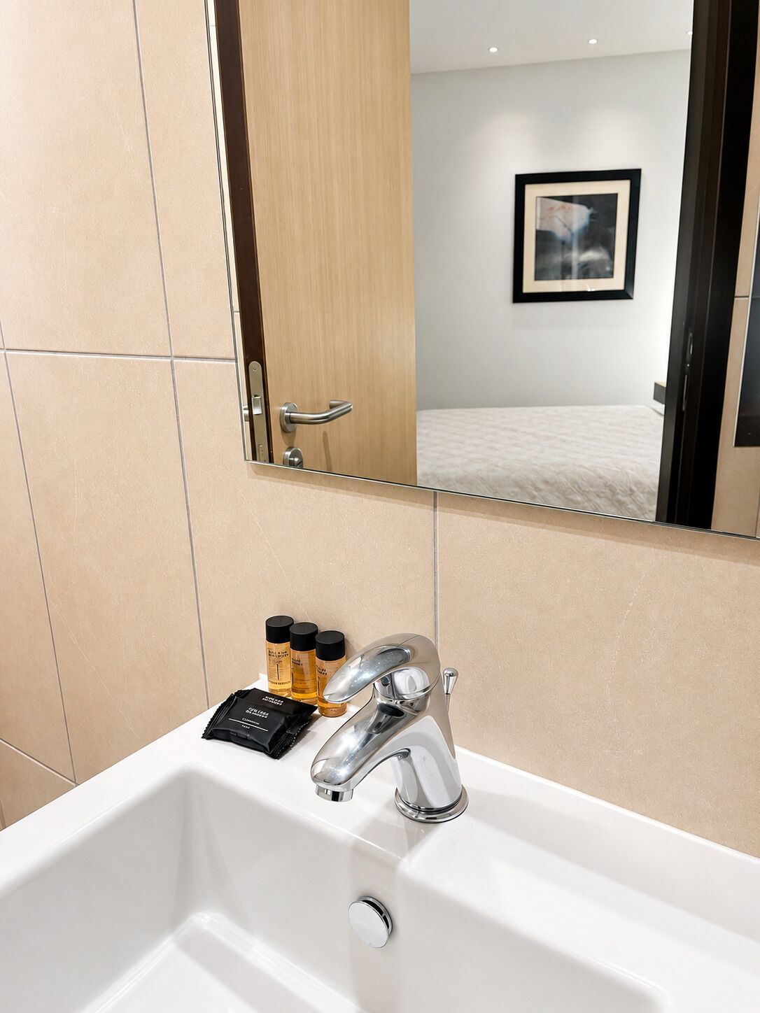 A bathroom with a white sink, a mirror, and toiletries.