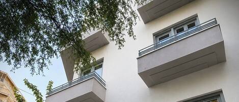 A modern hotel with a flat facade, multiple balconies, and large windows.