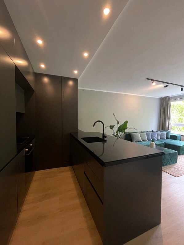 Una cocina moderna con una isla central, muebles oscuros e iluminación empotrada.