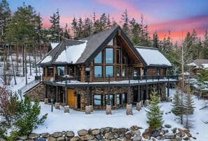 A log cabin with a stone foundation, large windows, and a balcony.