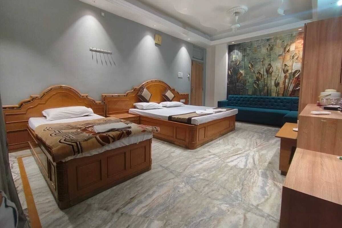 Een hotelkamer met drie houten bedden, een blauwe bank en een marmeren vloer.