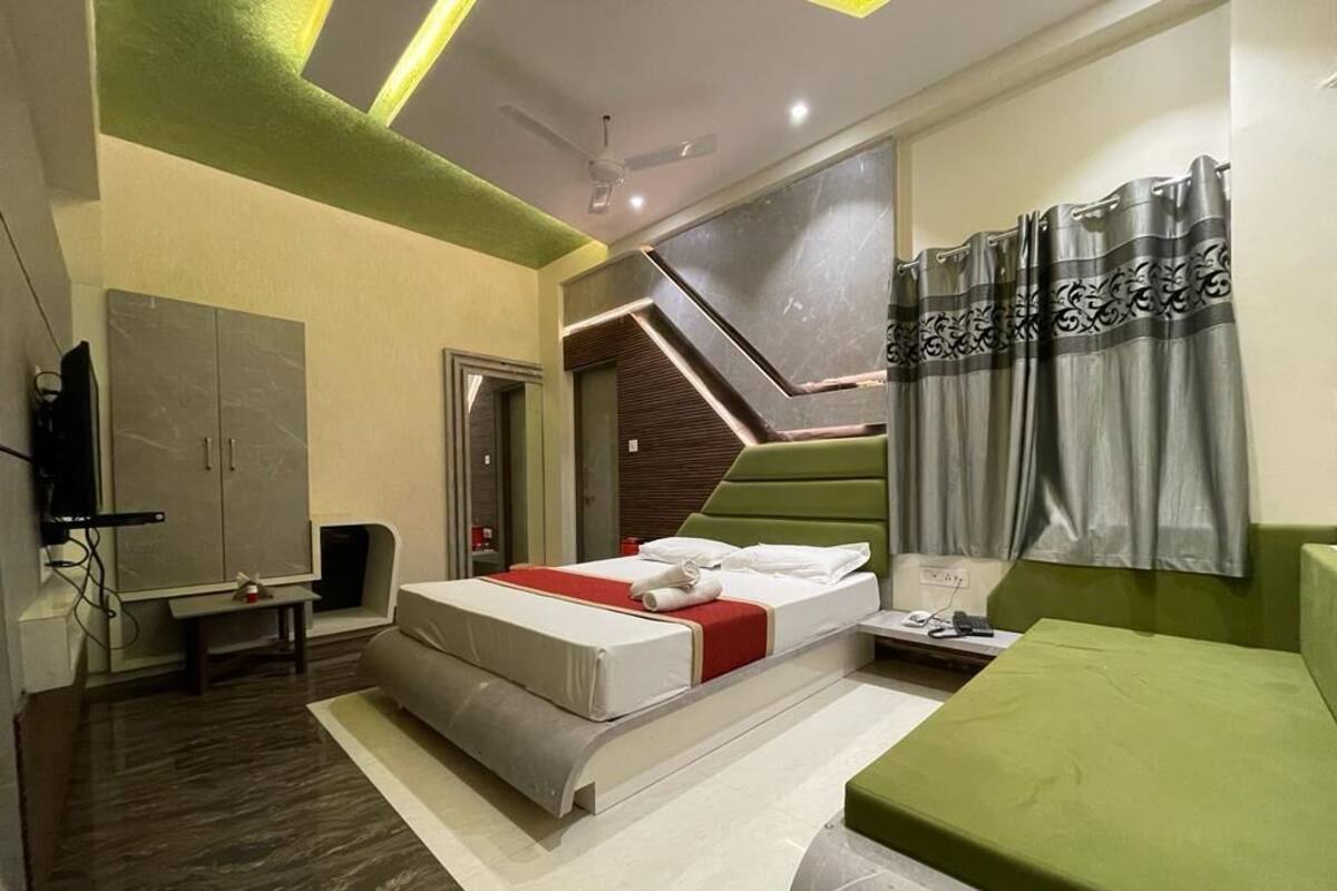 Een moderne hotelkamer met een bed, een groene bank, een bureau en een kledingkast.
