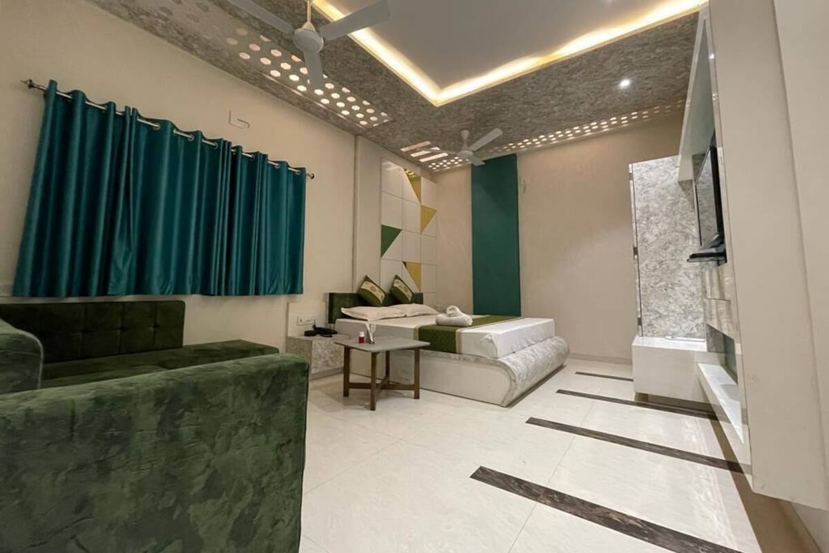 Een moderne woonkamer met een groene bank, een witte zithoek, een klein tafeltje en een plafondventilator.