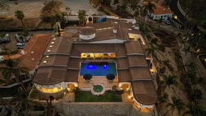 An aerial view of a resort with a central swimming pool, multiple guest villas, and a landscaped garden area. - Villa Tortuga: 5BR Beachfront Villa, Punta Bella near Palmilla, Palapa (San José del Cabo)