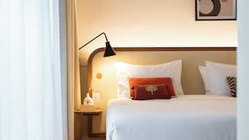 A neatly arranged hotel room with a bed, a nightstand, a lamp, and a framed picture on the wall.