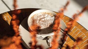 A cup of coffee on a saucer with a spoon, placed on a patterned tray.