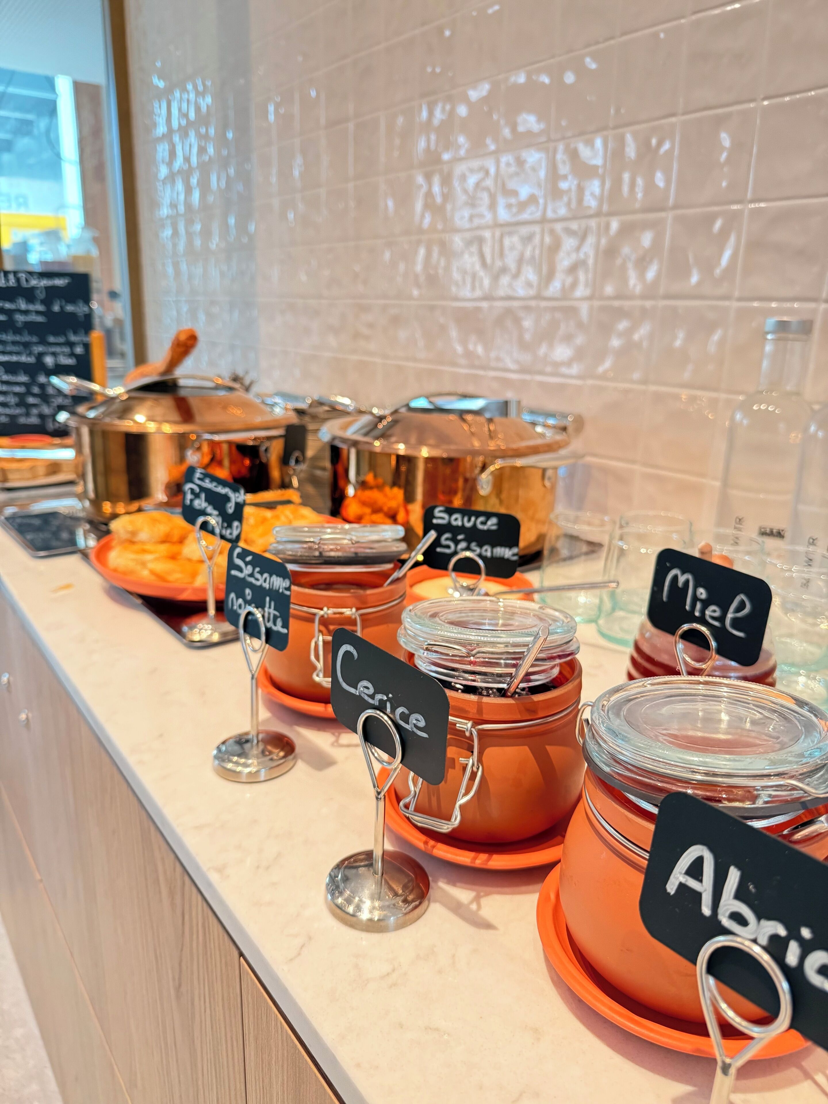 Un mostrador de buffet con recipientes etiquetados de salsas y condimentos.