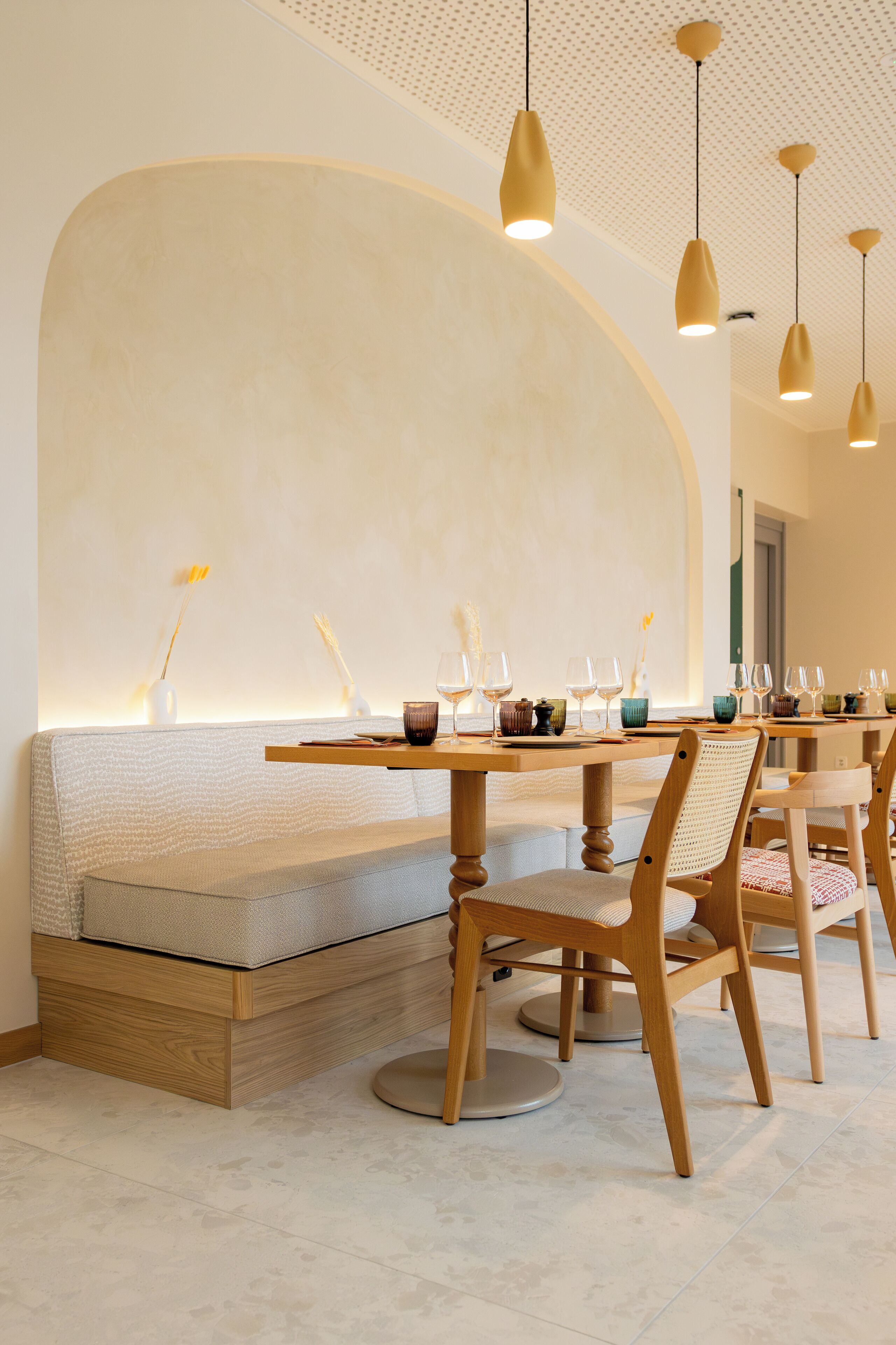 Un comedor con una mesa de madera larga, un banco acolchado e iluminación colgante.