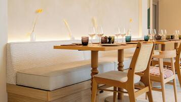 Un comedor con una mesa de madera larga, un banco acolchado e iluminación colgante.