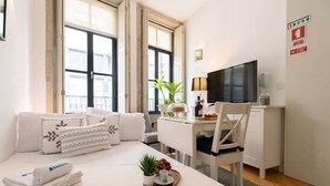 A hotel room with a bed, a desk, a chair, a television, and a window with a view of the outside. - Colourful Cozy Flat by HostWise (Porto)