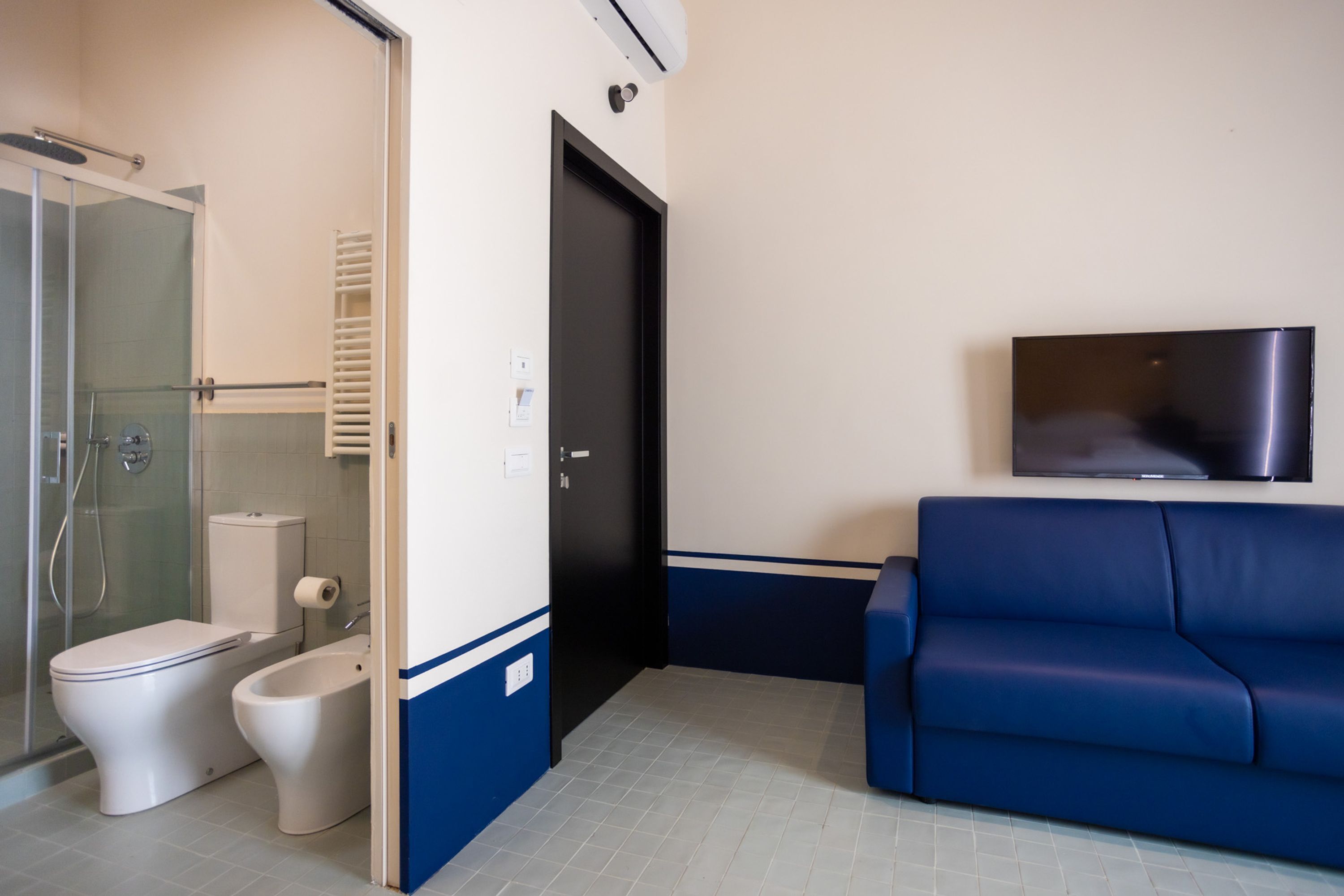 Un baño con inodoro, bidé y cabina de ducha de vidrio.