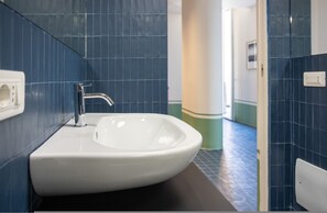 A bathroom with a white sink, blue tiled walls, and a dark floor.