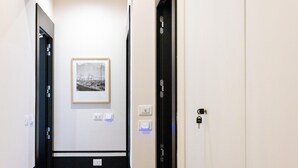 A hallway with a framed picture on the wall, a door with a lock, and a light switch. - Don Vittorio a Chiaia - Camera 4 (Naples)