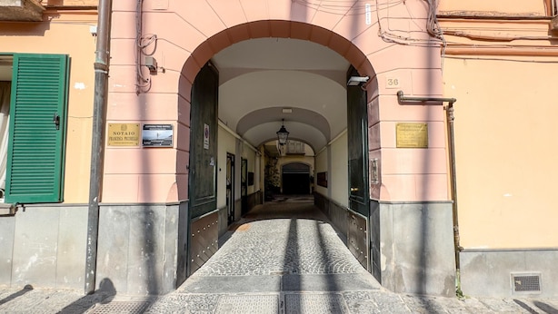 A corridor with an arched entrance, a tiled floor, and signs indicating a yoga studio and a legal studio. - Don Vittorio a Chiaia - Camera 4 (Naples)