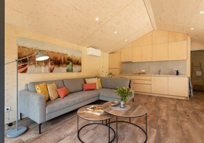 A modern living area with a sofa, coffee table, and a painting of a river scene. - Lodge with Sauna by the Water | Watervliet Oyster Lodge (Wissenkerke)