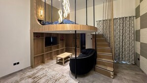 Ein modernes Wohnzimmer mit einer gebogenen Holzwand, einem schwarzen Sofa, einer Holzbank und einer Treppe.