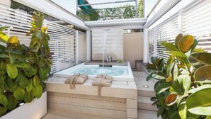 Un espace bien-être comprenant un jacuzzi, des serviettes et des plantes.