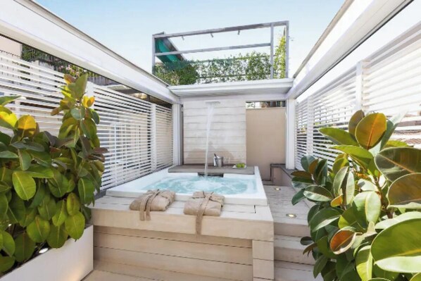 Een wellnessruimte met een jacuzzi, handdoeken en planten.