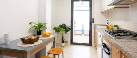 A modern kitchen with a built-in stove, a dining area with stools, and potted plants.