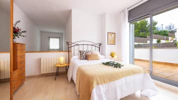 Un dormitorio con cama, mesita de noche, cómoda, ventana y vistas al exterior.