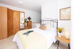 Un dormitorio con cama, mesita de noche, lámpara y armario.
