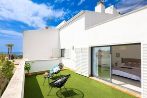 Un apartamento moderno con balcón, cama y vista al mar.