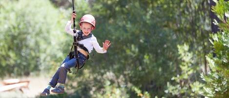 A person on a zip line in a wooded area.