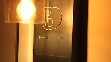 Een wandbord met het nummer 217 en de naam BONNIE CITY HOTEL, plus een lamp bovenop.