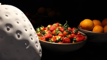 Eine Schale mit Erdbeeren und Orangen auf dunklem Untergrund.