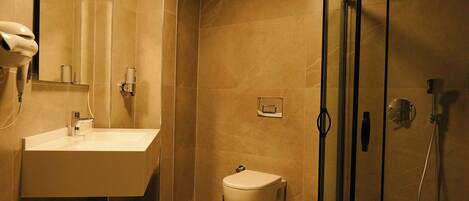 Un baño moderno con lavamanos, inodoro y cabina de ducha con mampara de vidrio.
