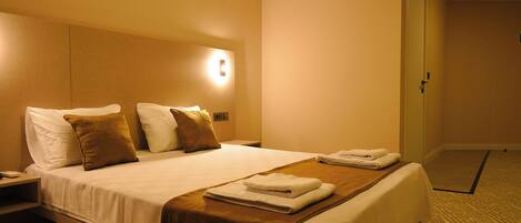 Une chambre d’hôtel avec un grand lit, une table de chevet, un climatiseur fixé au mur et une porte.