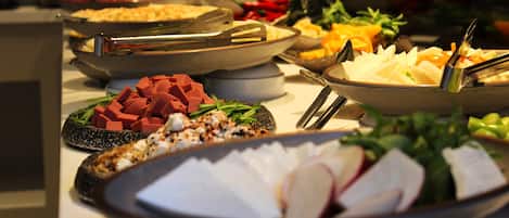 A buffet with various dishes including meats, cheeses, and vegetables.
