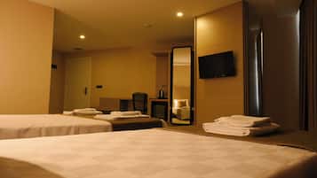 Habitación de hotel con dos camas, un espejo grande, un televisor de pantalla plana y un baño visible a través de una puerta abierta.