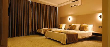 A hotel room with two beds, a large window with curtains, an air conditioning unit, and a carpeted floor.