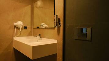 A bathroom with a white sink, a mirror, and a hairdryer mounted on the wall.