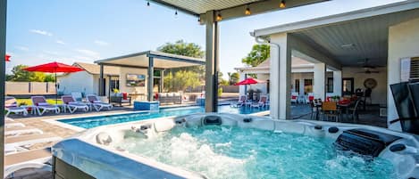 Un bain à remous avec un espace piscine, des chaises longues et des parasols.