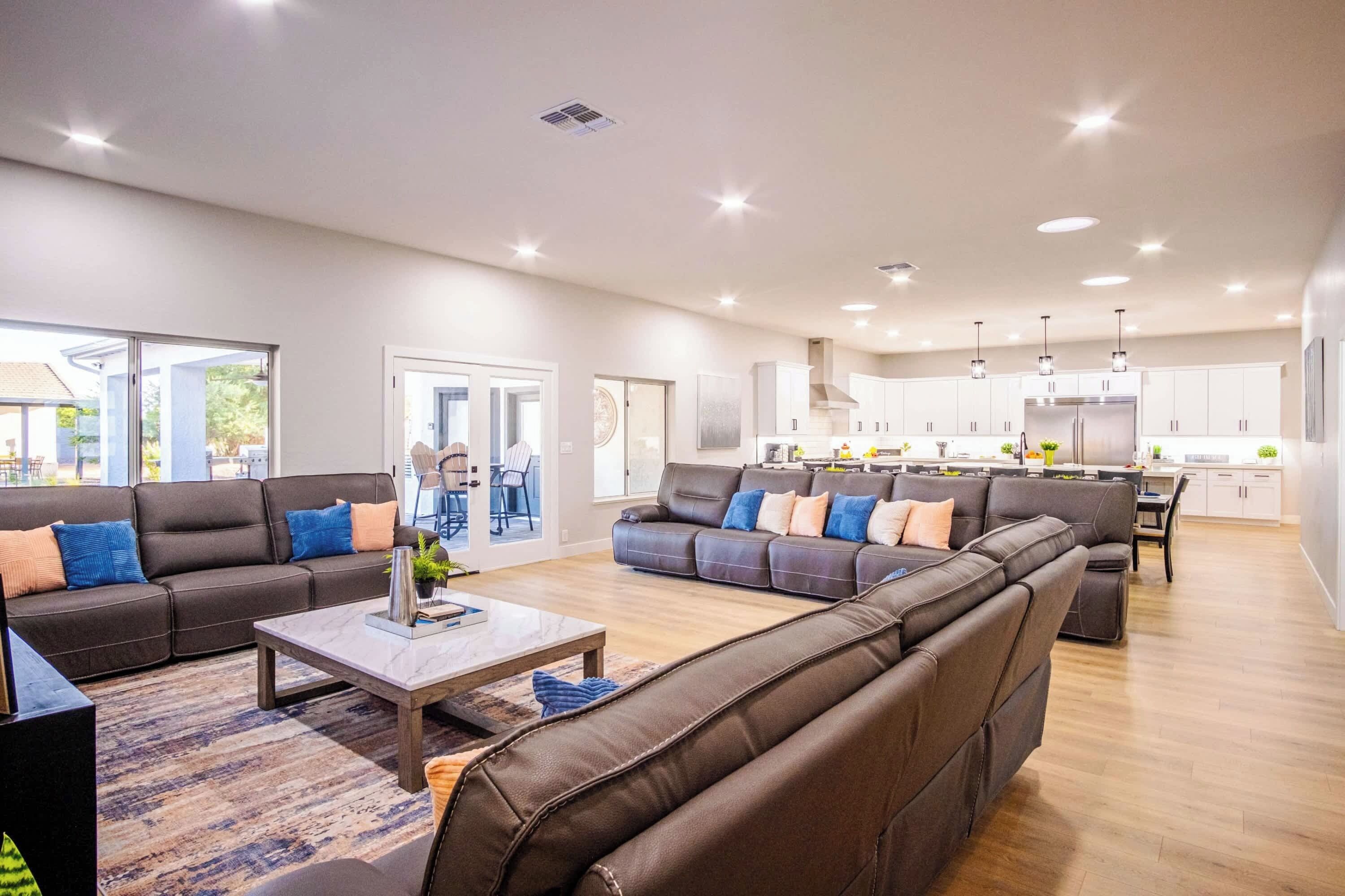 A spacious living room with a large sectional sofa, a coffee table, and a dining area in the background.
