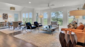 A spacious living room with a glass coffee table, a sofa, and a dining area with chairs and a table. - Award-Winning Resort Amenities | Marsh Island 30 (Isle of Palms)