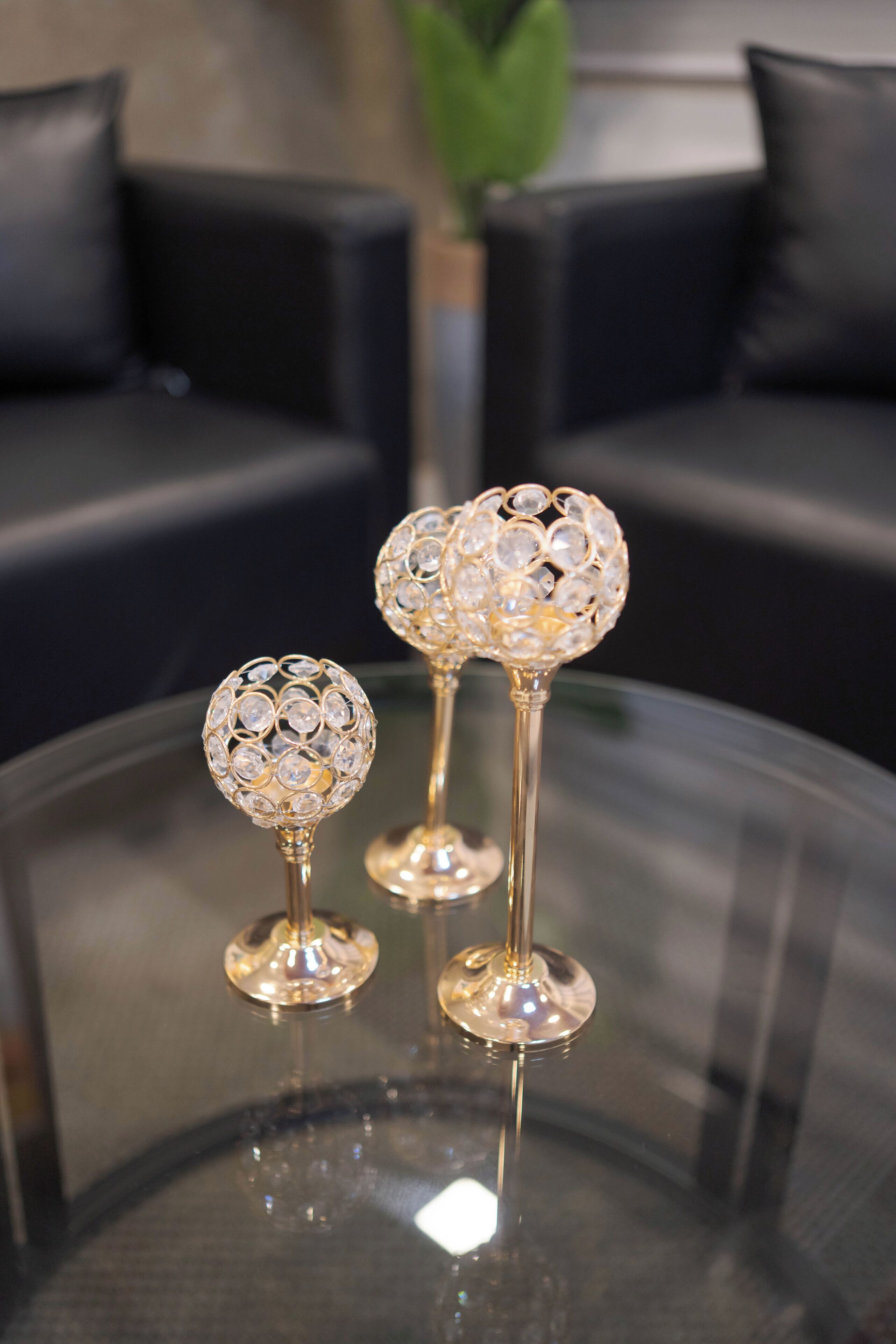 Three crystal glass candle holders on a glass table.